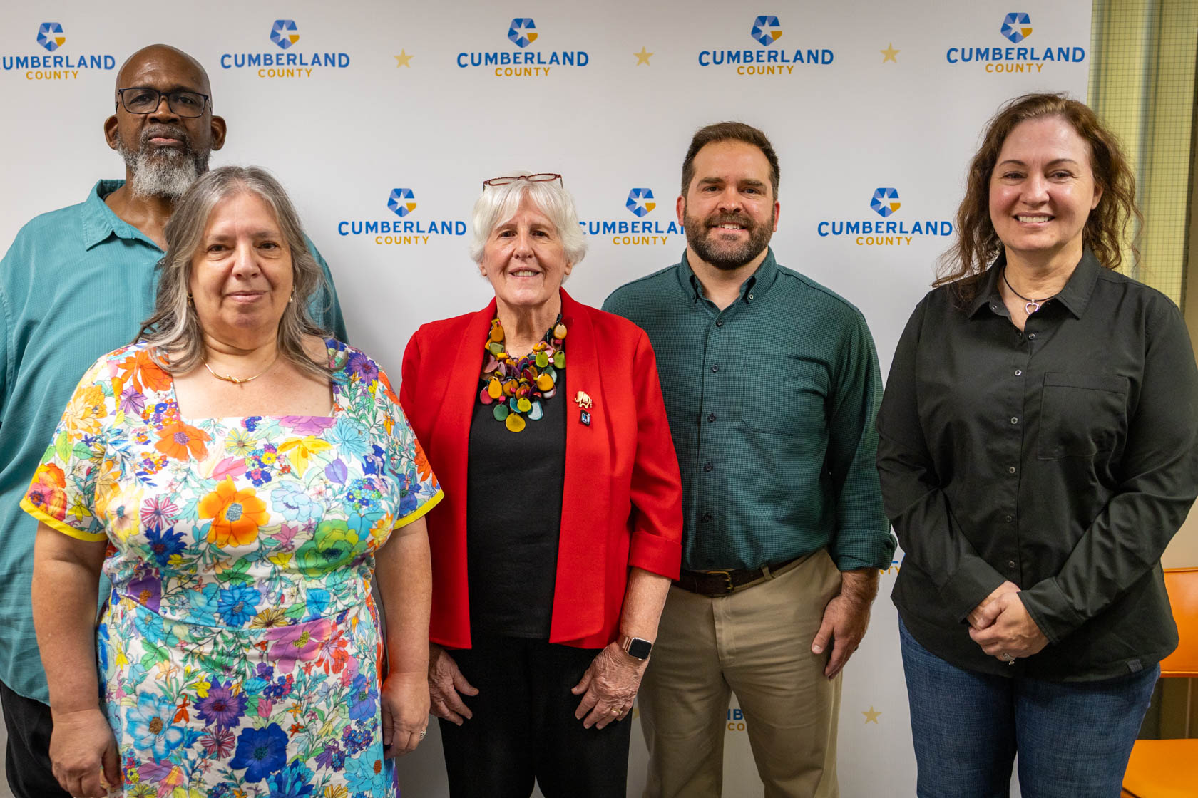 Five people standing in front of a Cumberland County logo backdrop.