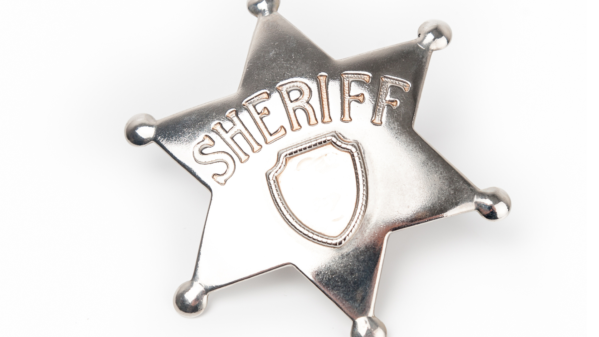 Close up of a silver sheriff star on a white background.