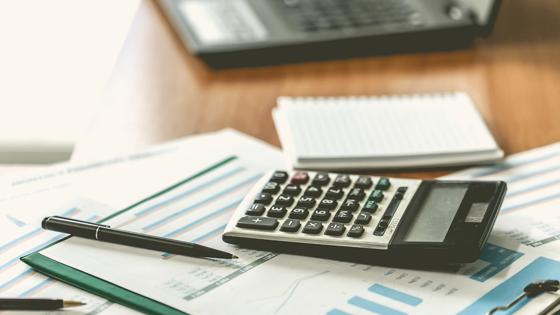 Calculator on top of desk with pencils and spreadsheets.